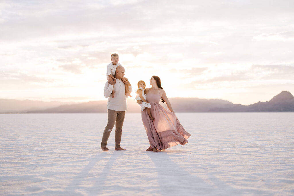 Family Picture at the Salt Flats in Utah. Family Looks at each other with the sunset behind them.