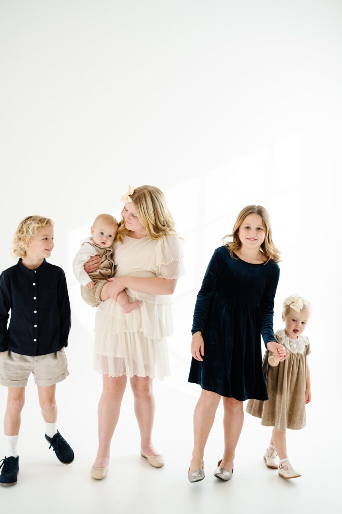 Children walking together and holding hands in their studio family pictures in Utah. 